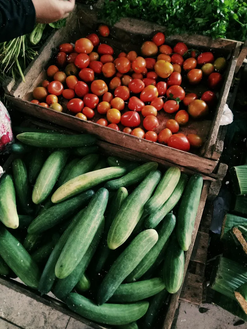 Verse tomaten en komkommers in houten kratten op een boerenmarkt
