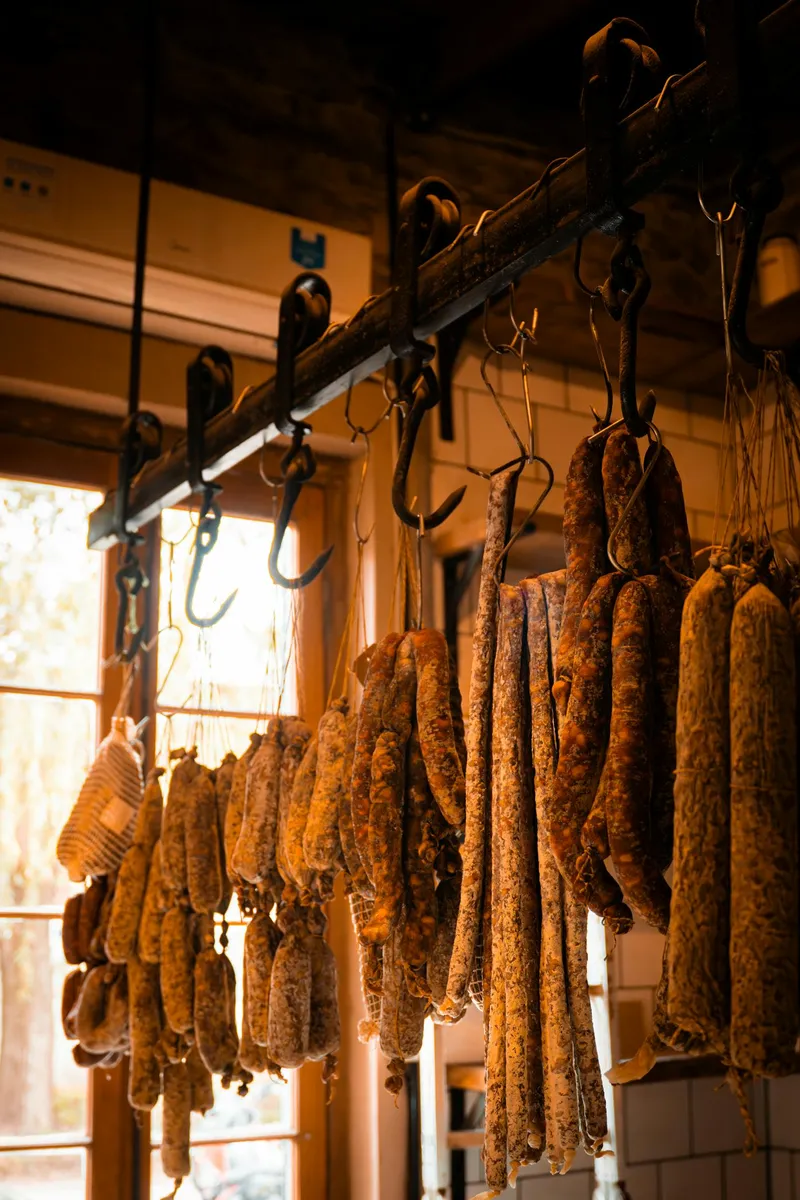 Gedroogde worsten en charcuterie hangend in een ambachtelijke werkplaats